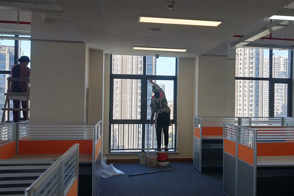 兩名清潔公司員工在辦公室清潔窗戶。